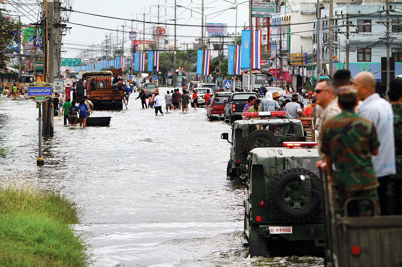 ประชาชนเดินลุยน้ำท่วมบนถนนที่มีน้ำสูงถึงเอว