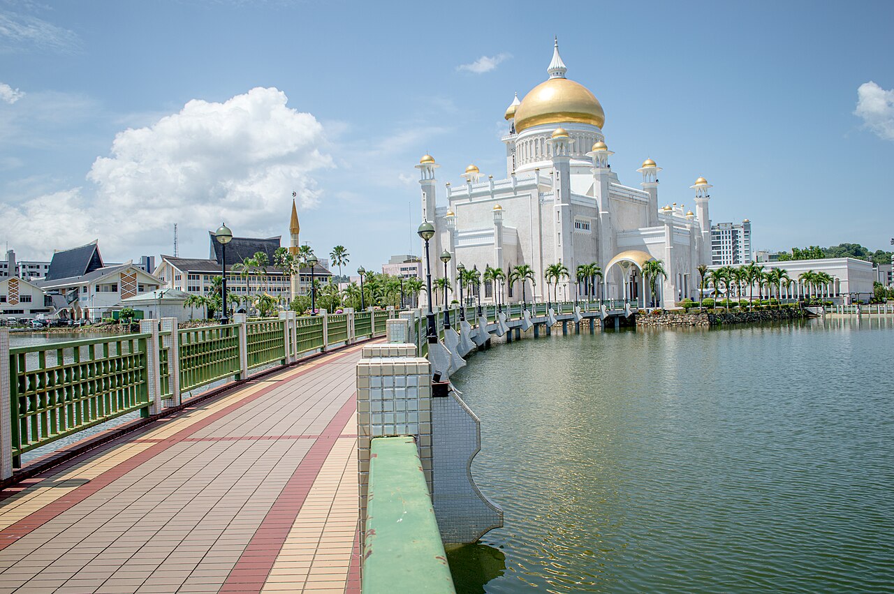 ทางเดินริมทะเลสาบทอดยาวไปยังมัสยิดสีขาวโดมทอง ท้องฟ้ามีเมฆ